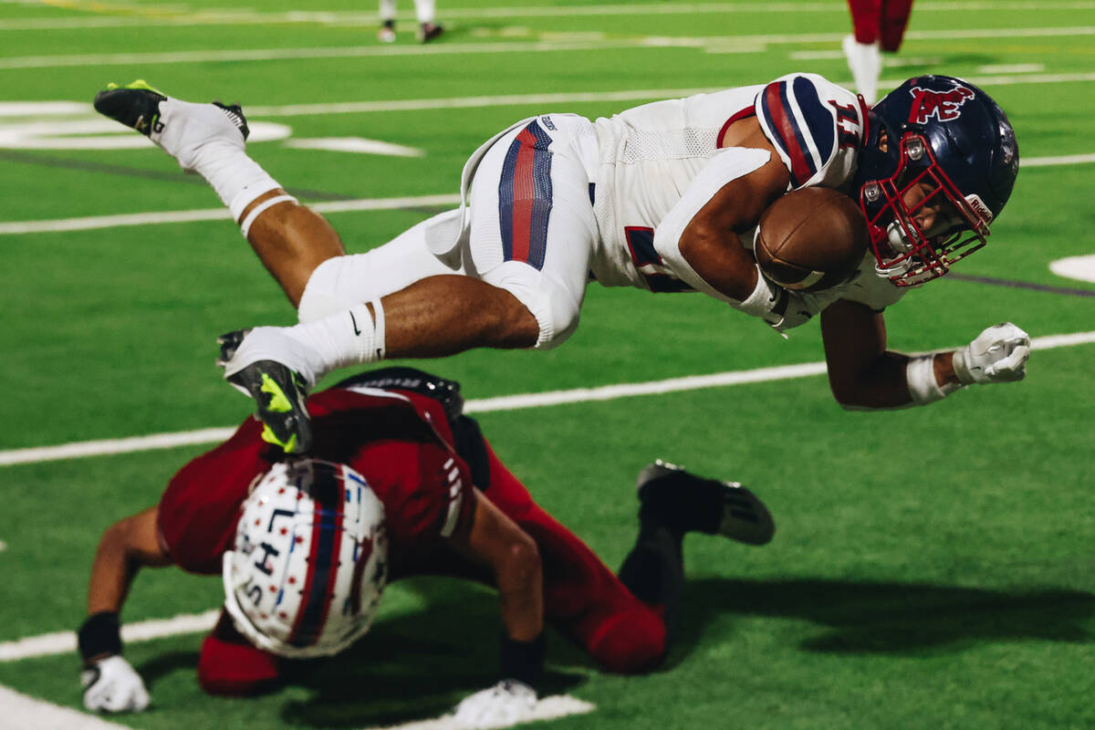 St. Louis slotback Titan Lacaden (11) dives over Liberty cornerback Peyton Caldwell (20) with t ...