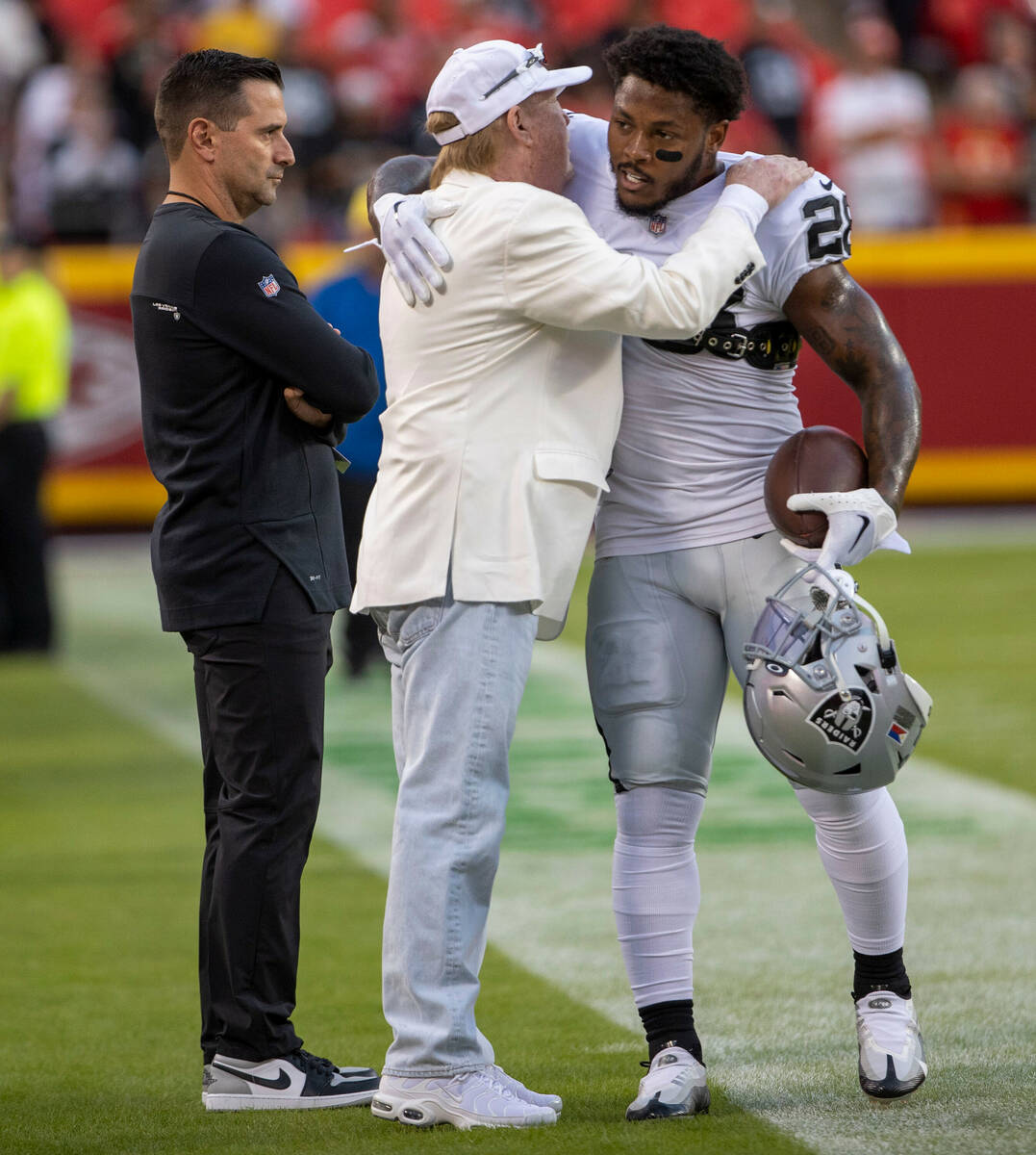 Raiders owner Mark Davis, center, hugs Raiders running back Josh Jacobs (28) as general manager ...