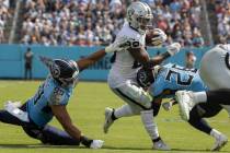 Raiders running back Josh Jacobs (28) breaks through a hole past Tennessee Titans linebacker Ra ...