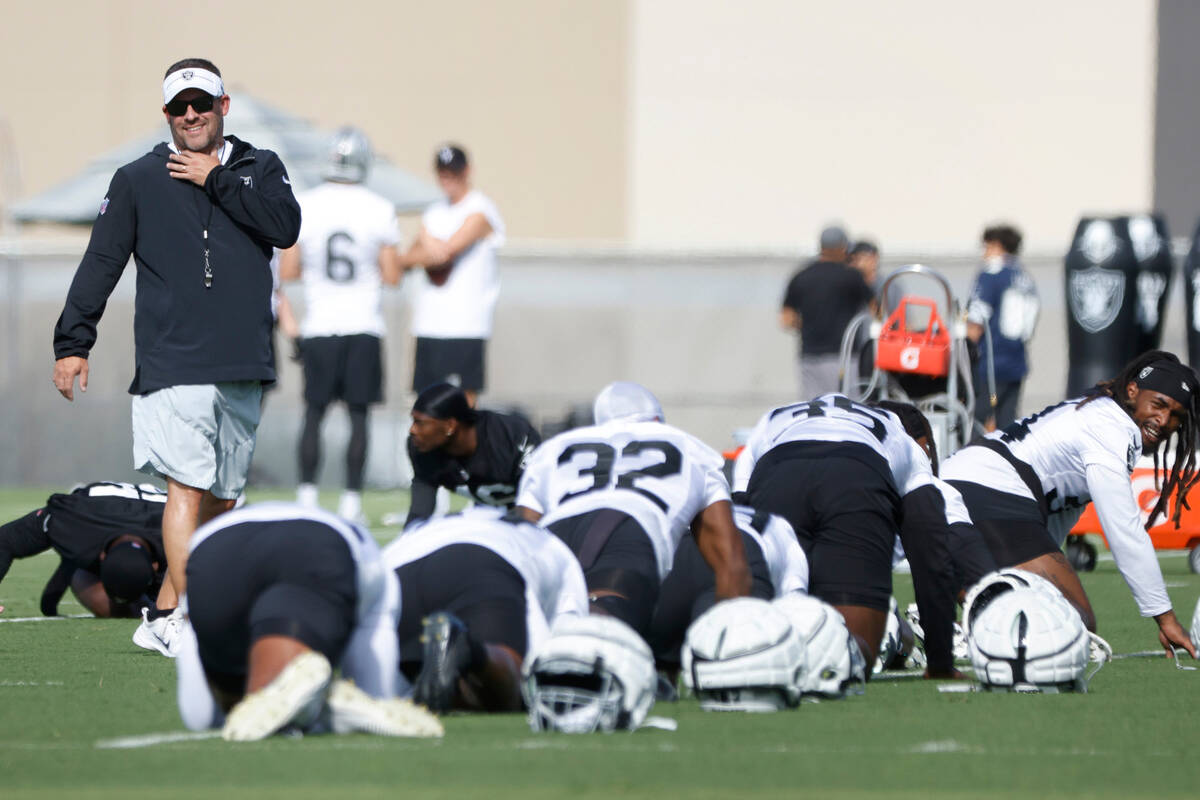 Raiders head coach Josh McDaniels watches as his players stretch during training camp at the In ...