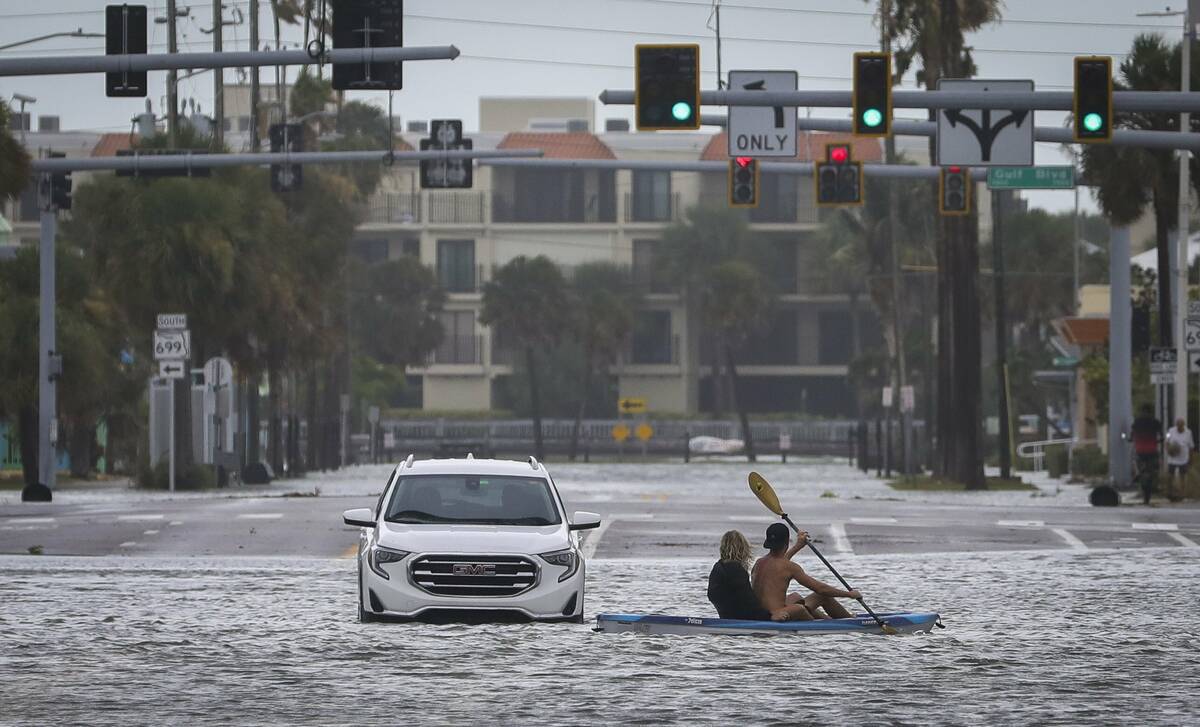 People kayak past an abandon vehicle in the intersection of Boca Ciega Drive and Pasadena Avenu ...