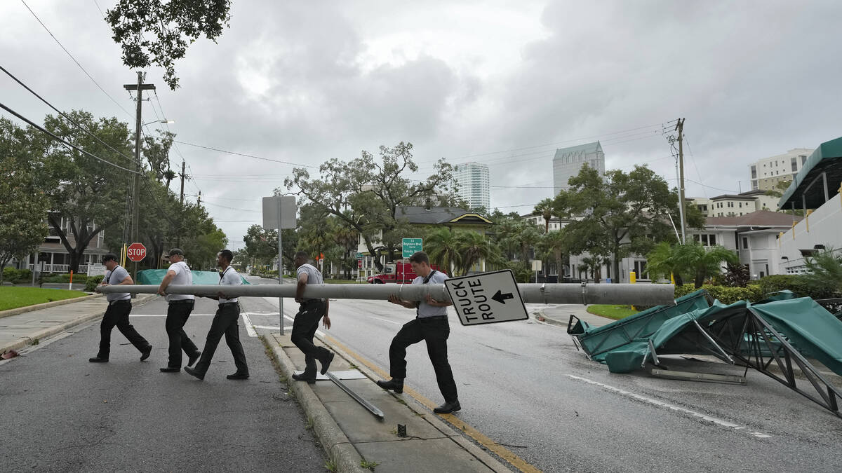 Members of the Tampa Fire Rescue Dept., remove a street pole after large awnings from an apartm ...