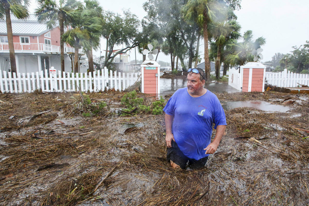 Daniel Dickert wades through water in front of his home where the Steinhatchee River overflowed ...