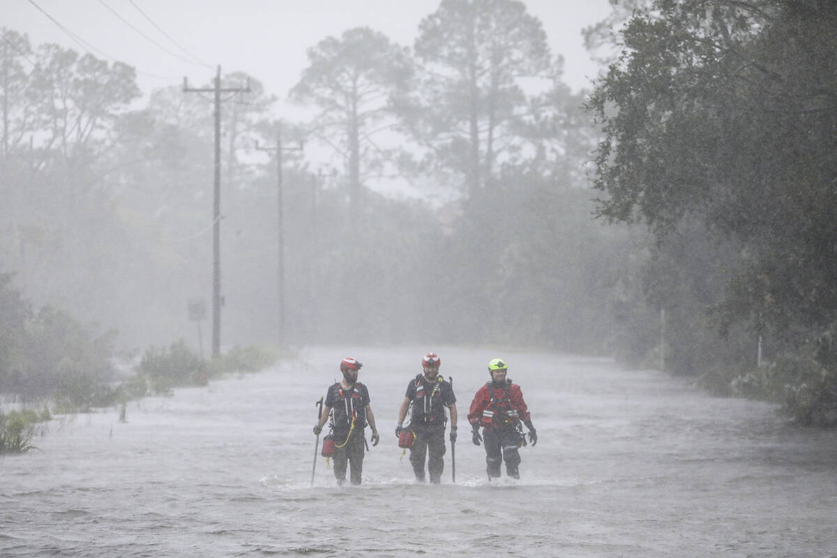 Rescue workers with Tidewater Disaster Response wade through a tidal surge on SW 358 Highway wh ...