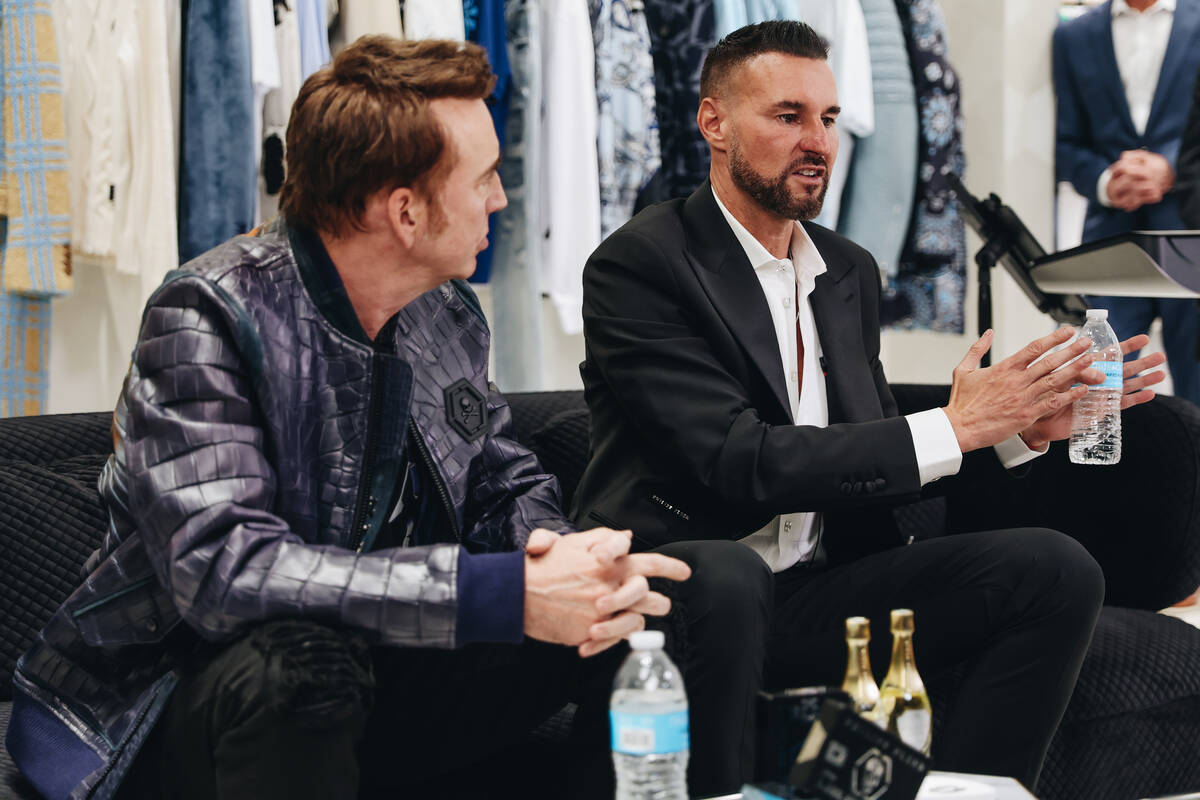 Philipp Plein, right, speaks to the media as Nicolas Cage listens to him speak during a grand o ...