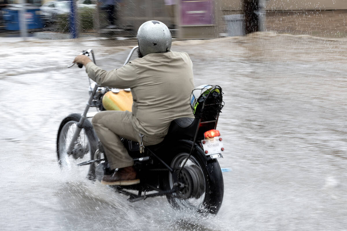 A motorcyclist makes way through flood waters on East Sahara Avenue at South Eastern Avenue on ...