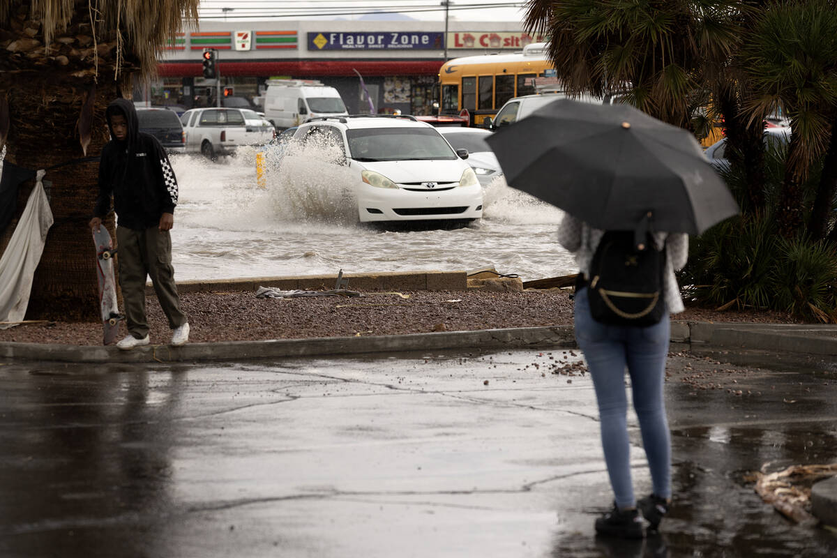 Pedestrians stop to watch flash flooding at the intersection East Sahara Avenue and South Easte ...