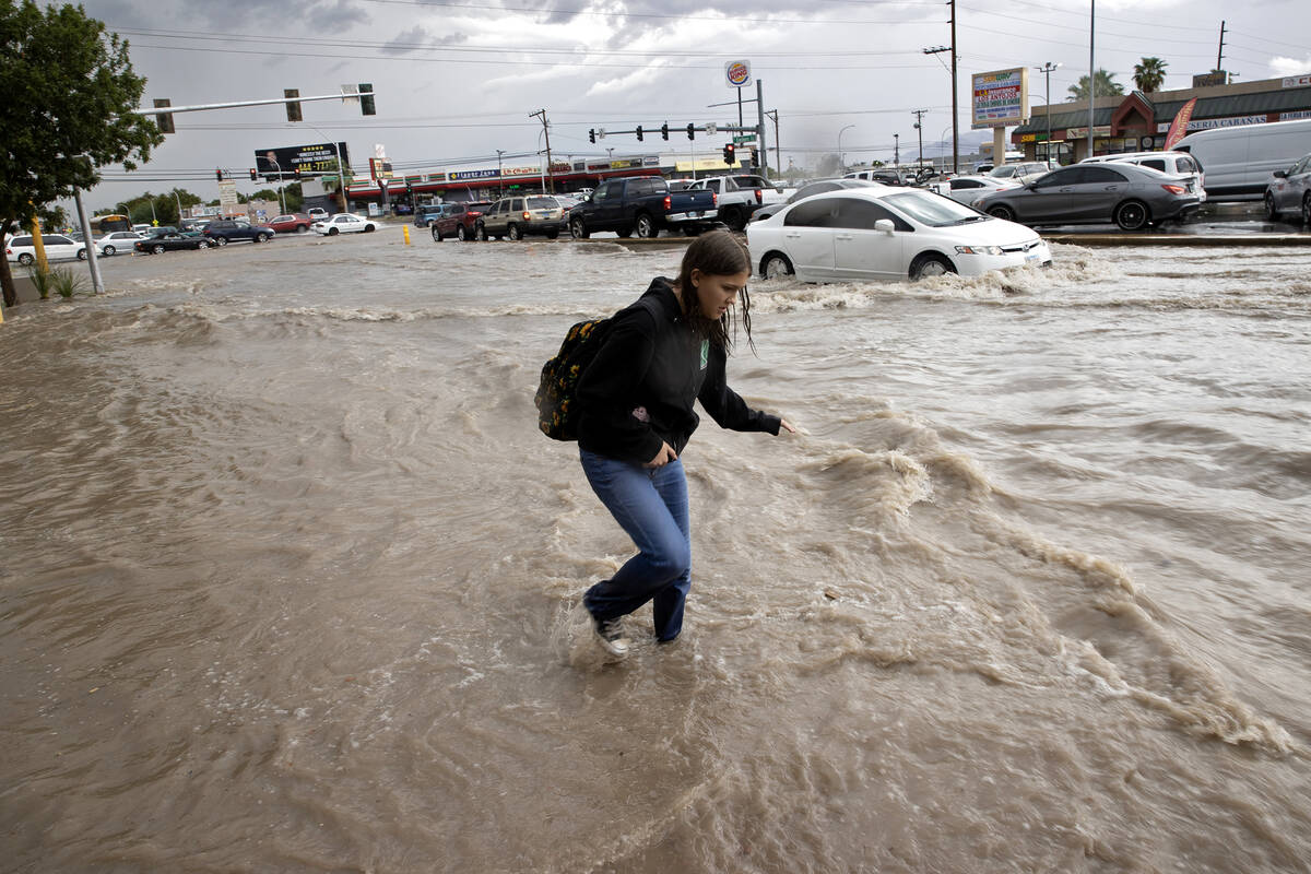 A pedestrian walks down a flooded sidewalk on South Eastern Avenue on Friday, Sept. 1, 2023, in ...