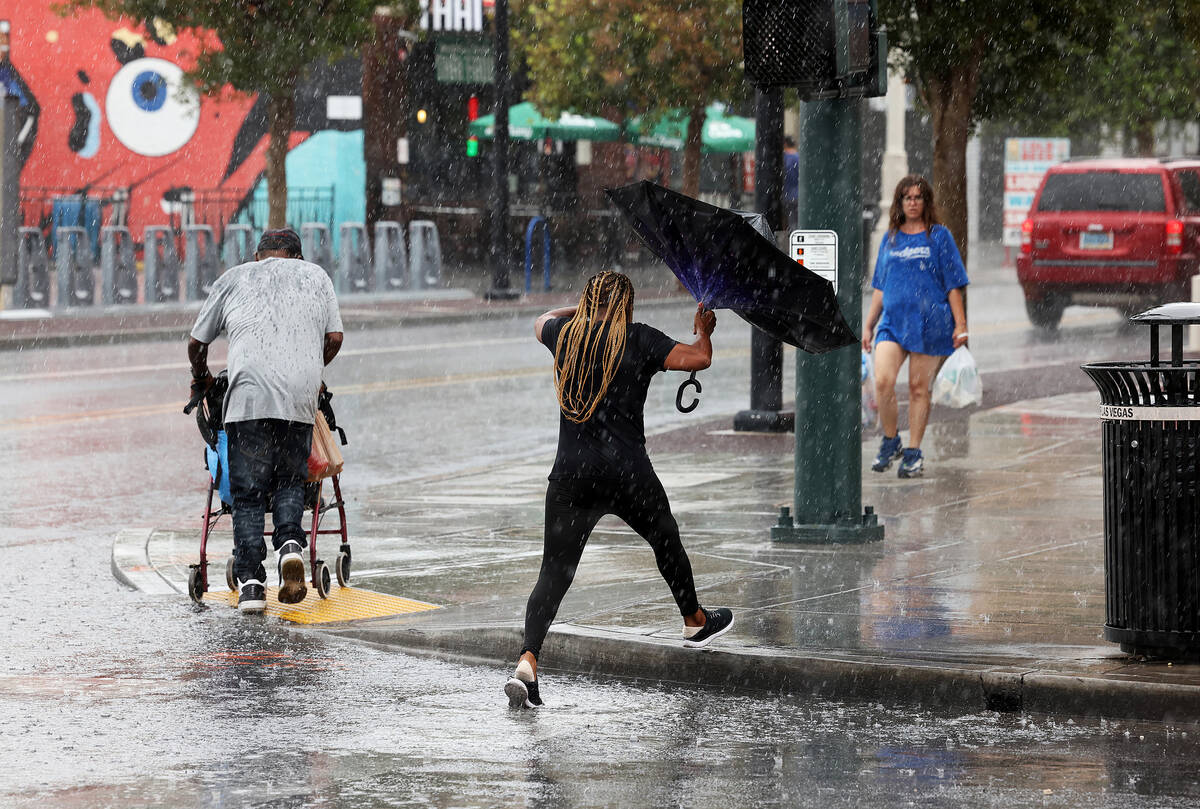 People brave the rain on East Fremont Street in downtown Las Vegas on Friday, Sept. 1, 2023. (K ...