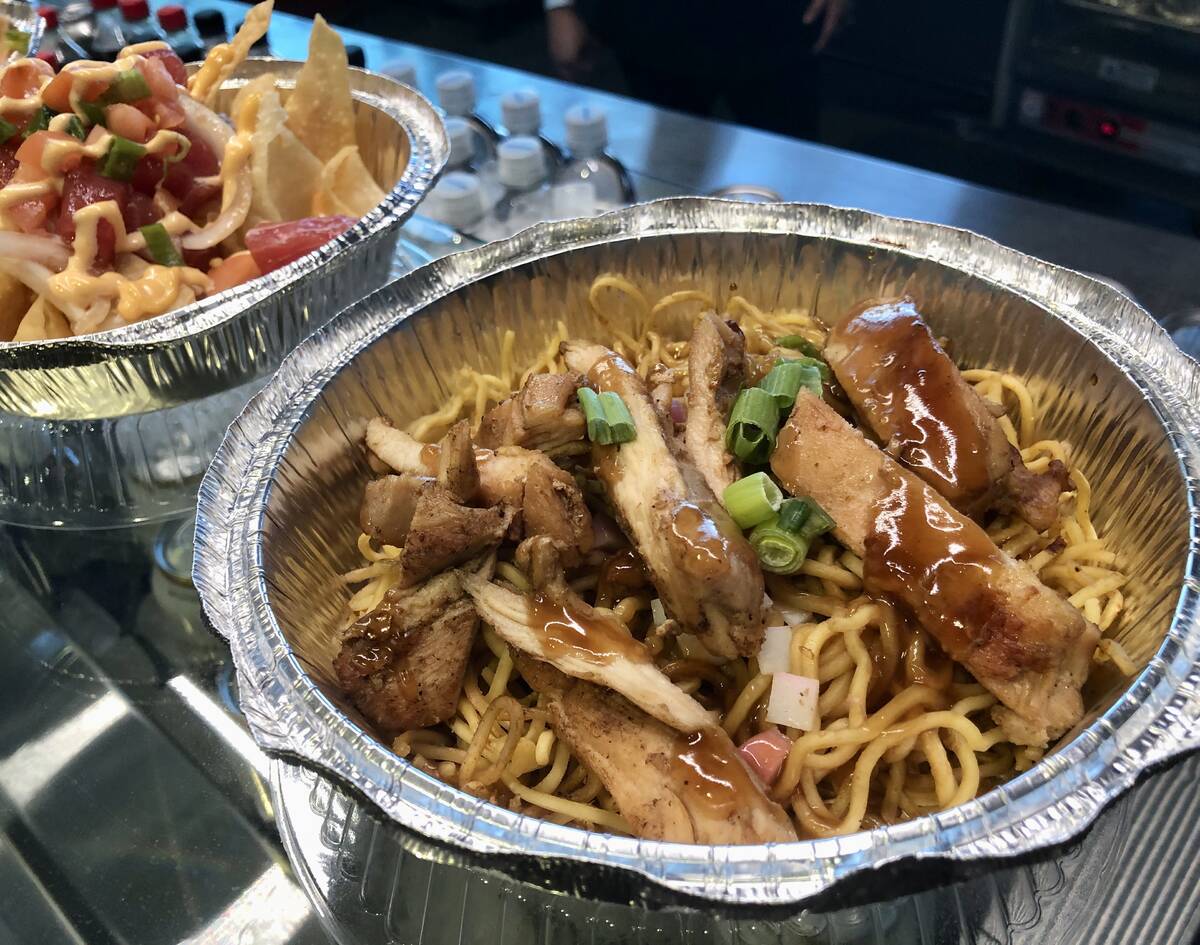 Fried noodles with teriyaki chicken, front, and ahi nachos, from Island Flavor at Allegiant Sta ...