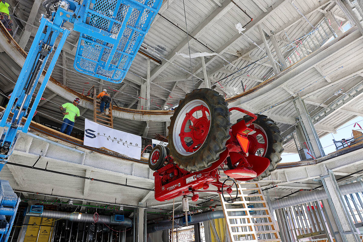 Workers raise an antique tractor for installation on the ceiling of the under construction Blak ...