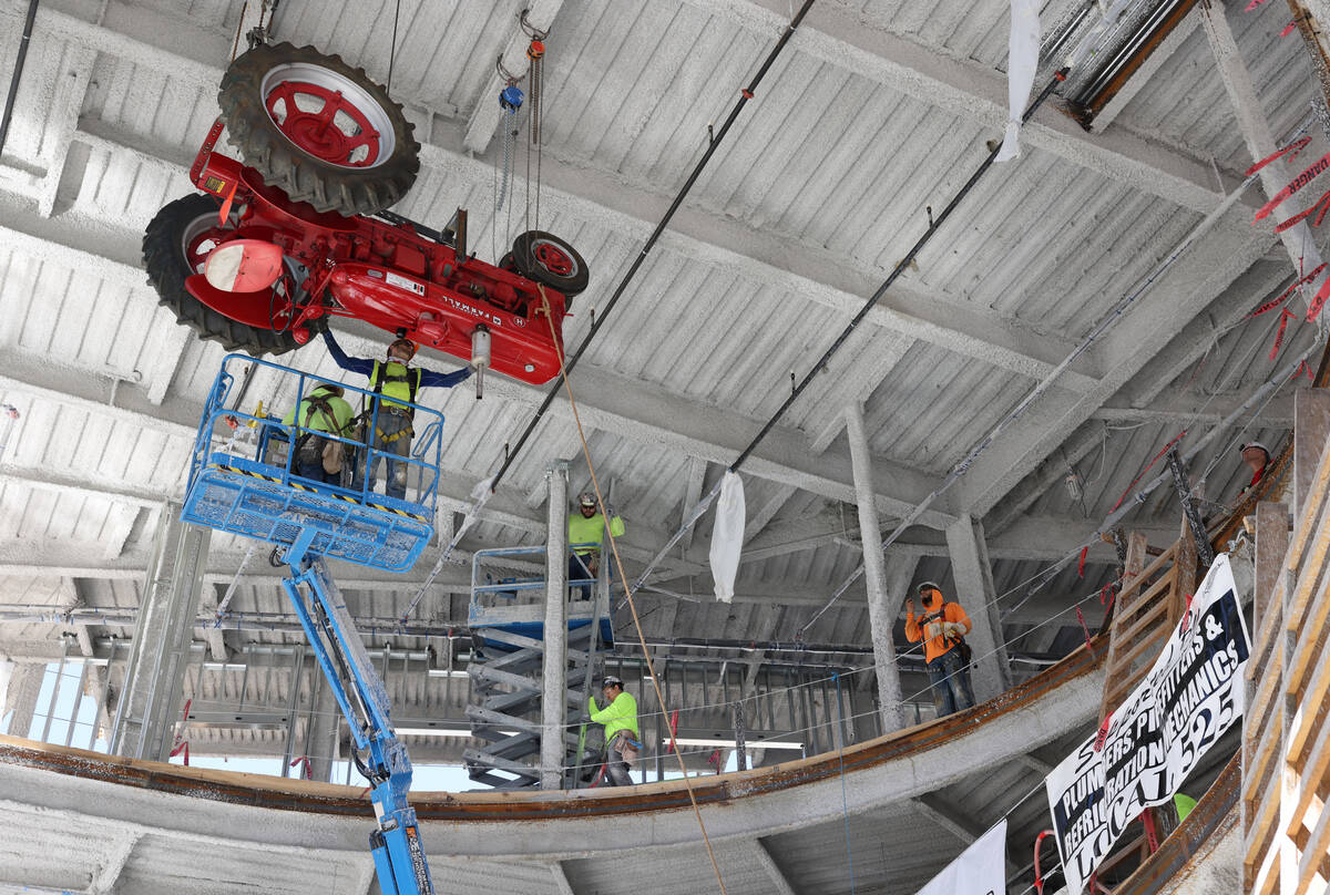Workers raise an antique tractor for installation on the ceiling of the under construction Blak ...