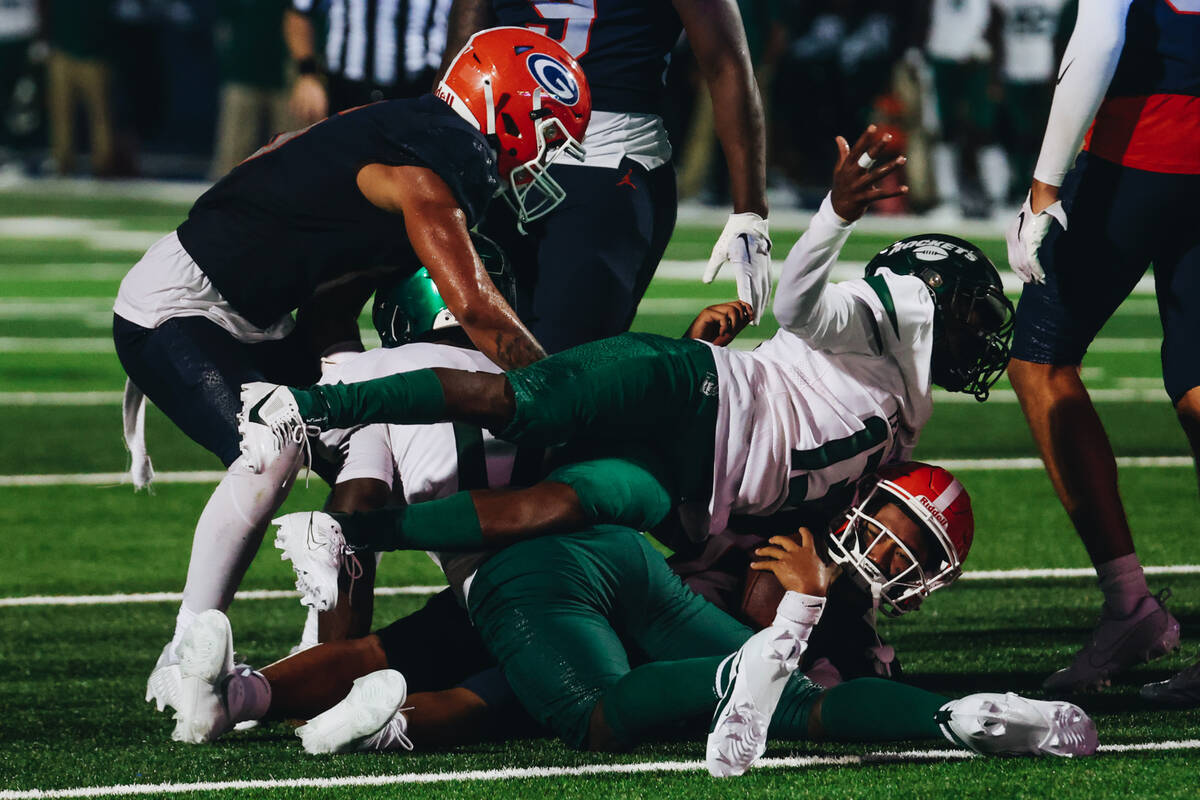 Bishop Gorman quarterback Micah Alejado (12) is crushed by Miami Central players after running ...