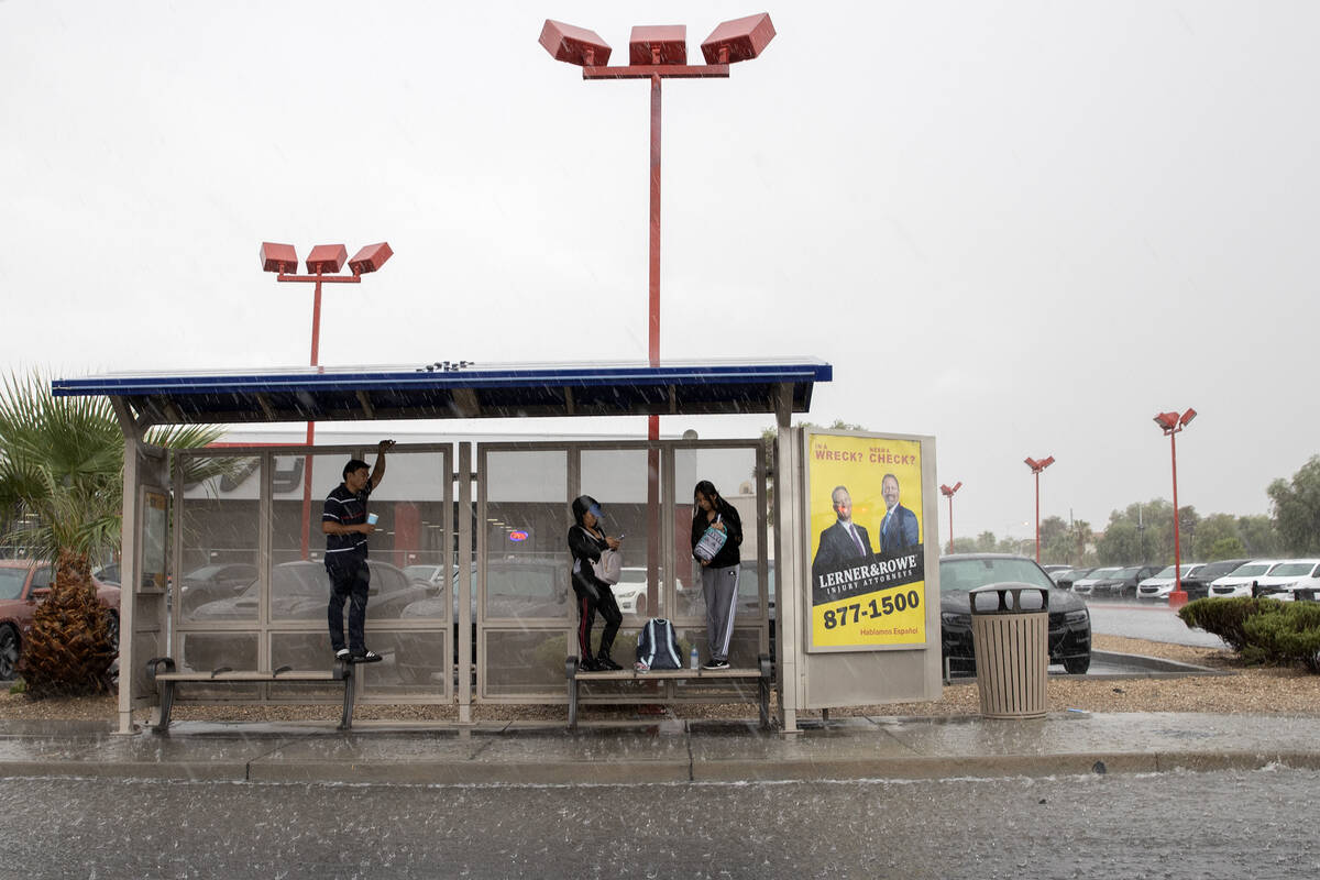 People shield themselves from rain in a bus shelter on East Sahara Avenue on Friday, Sept. 1, 2 ...