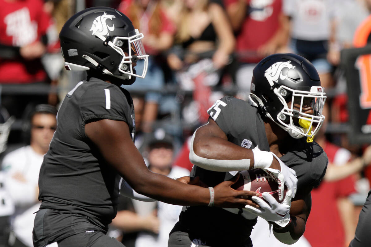 Washington State quarterback Cameron Ward (1) hands the ball off to running back Nakia Watson ( ...