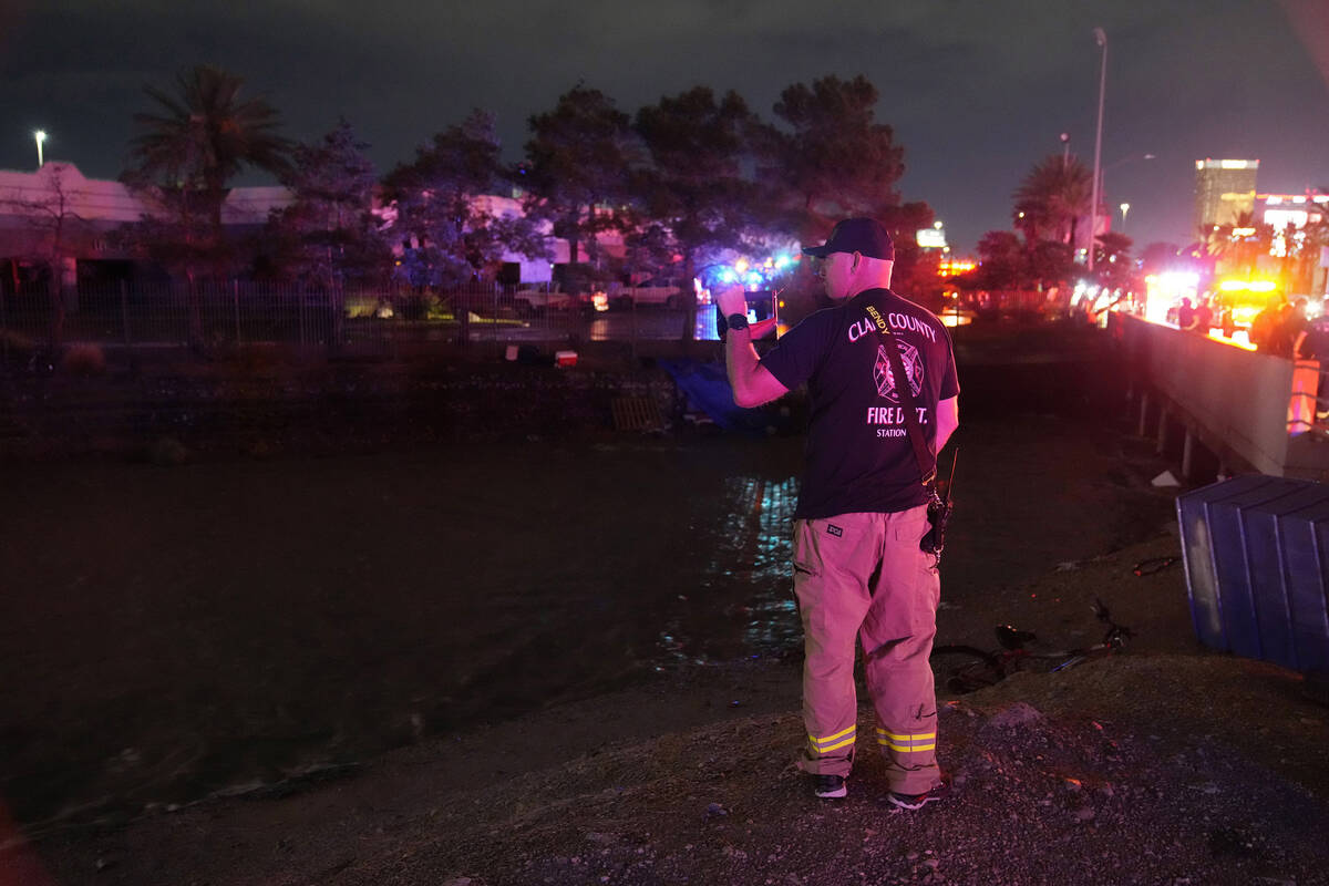 A Clark County Fire Department official searches for people in floodwaters in a flood channel F ...