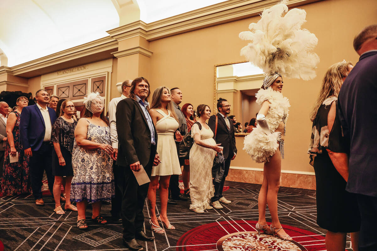 A showgirl walks with married couples into the Octavius Ballroom for a vow renewal ceremony at ...