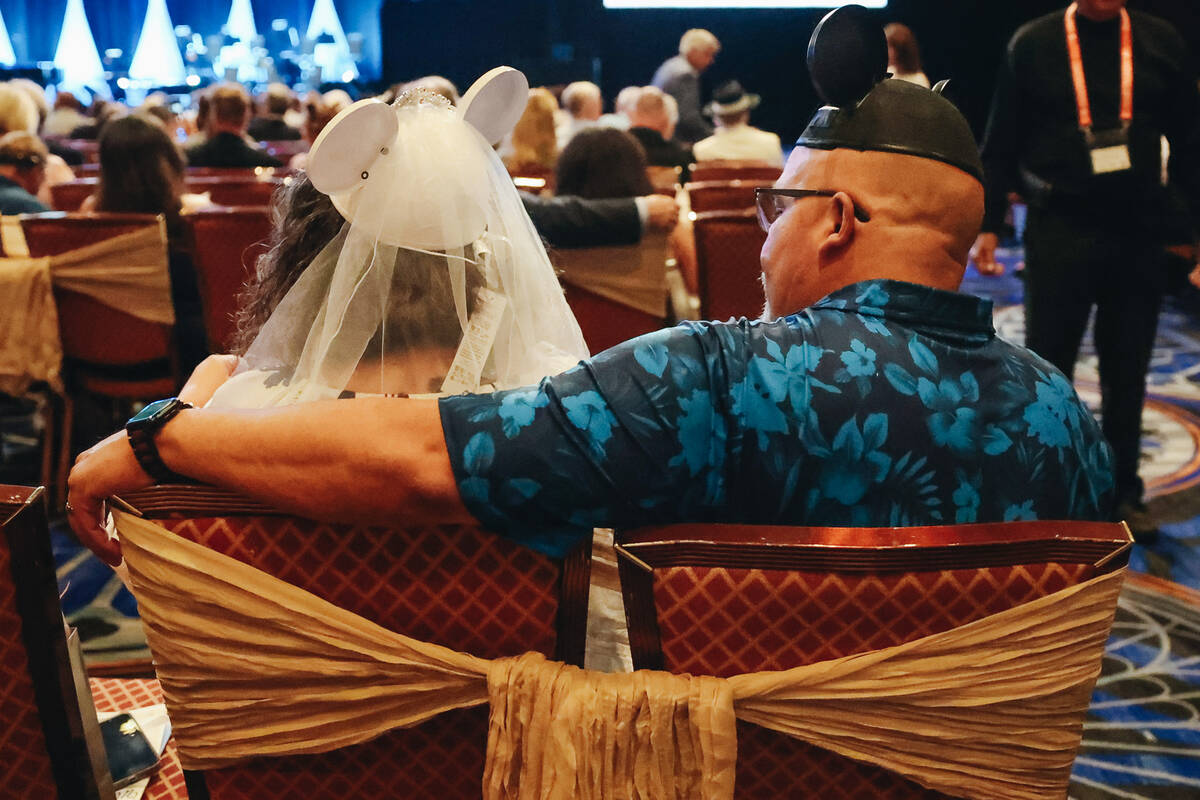 A couple in matching Minnie and Mickey Mouse ears sits down at a wedding renewal ceremony at Ca ...