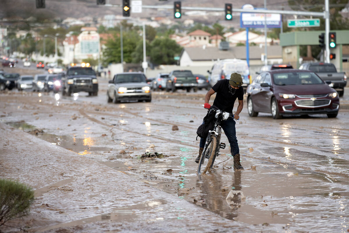 A bicyclist navigates muddy roads down East Lake Mead Boulevard on Saturday, Sept. 2, 2023, in ...