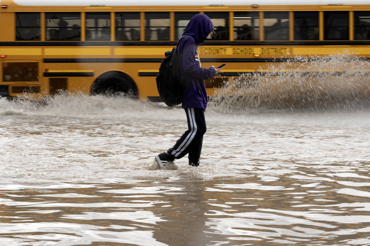 A pedestrian walks down a flooded sidewalk on South Eastern Avenue on Friday, Sept. 1, 2023, in ...