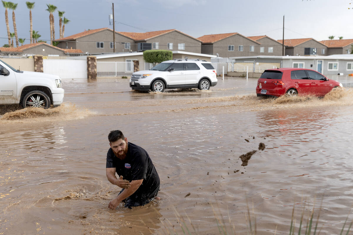 Tim Williams, a neighborhood resident, removes debris from a storm drain on Saturday, Sept. 2, ...