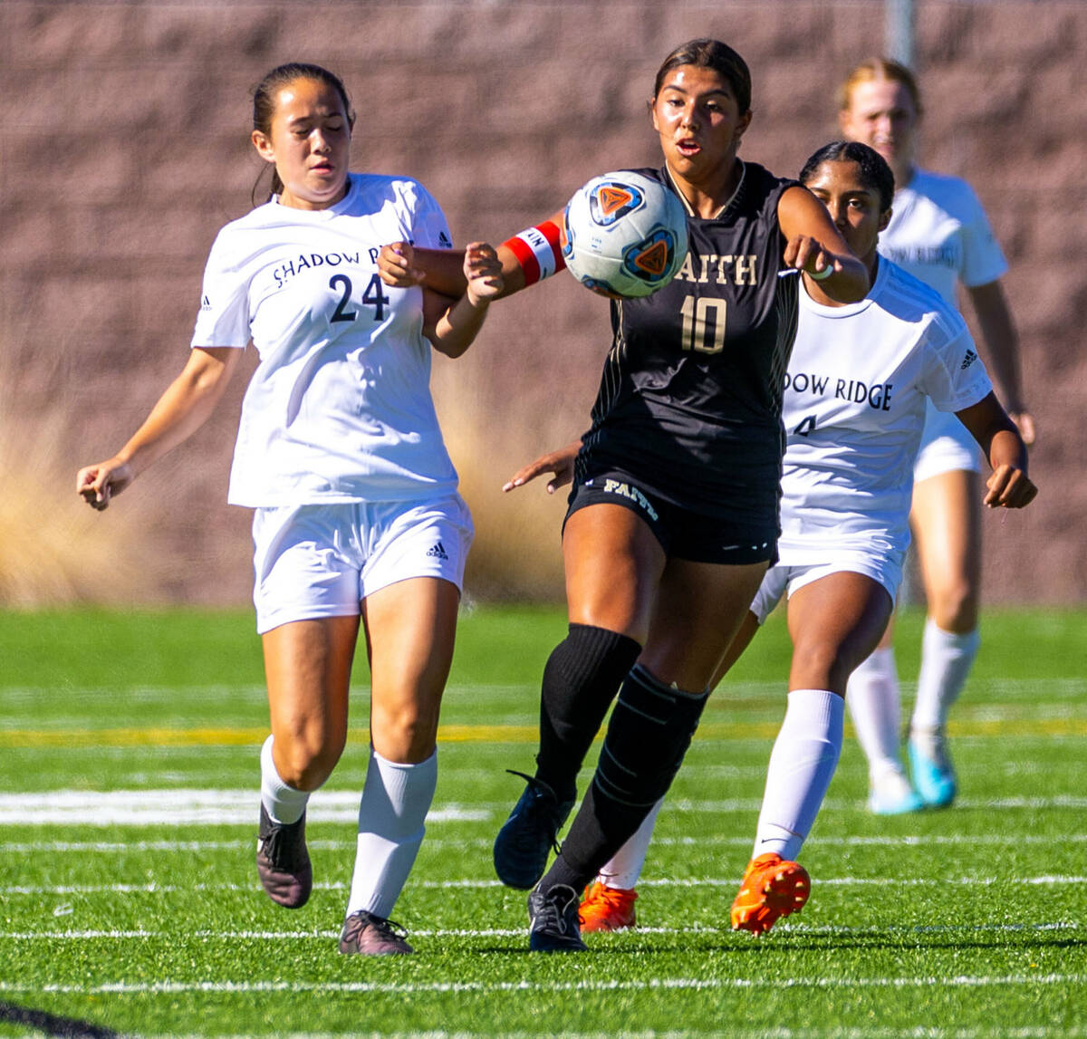 Shadow Ridge midfielder Leighanne Kim (24) fights for the ball while pushed by Faith Lutheran m ...