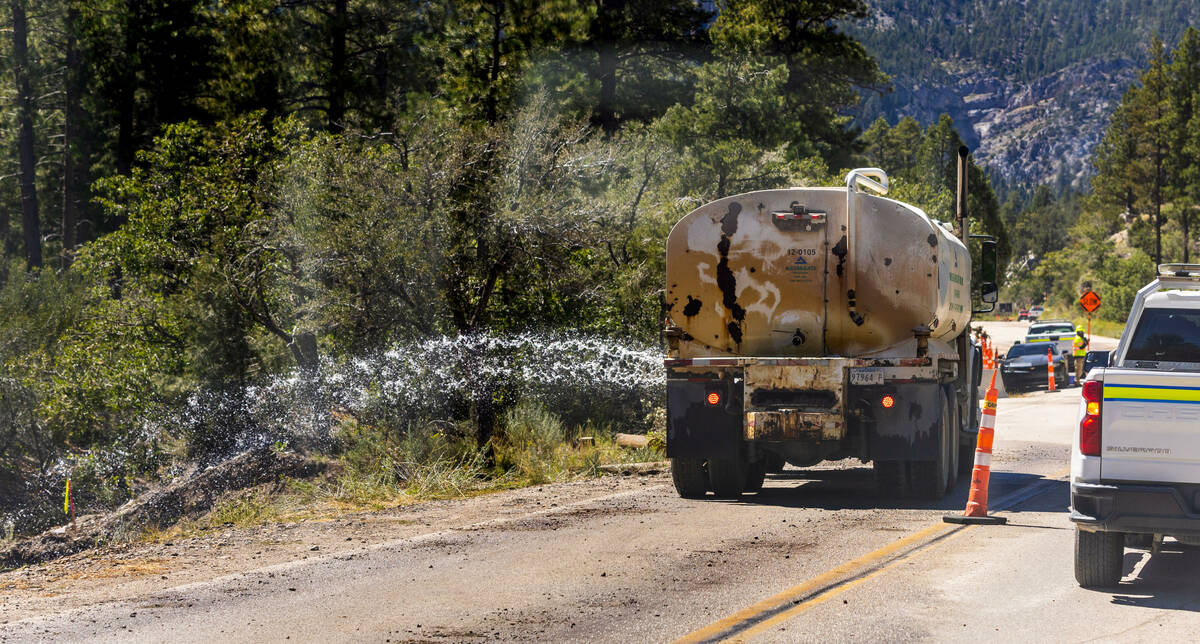 Water is sprayed on compacted earth for a new roadway along Kyle Canyon Road on Mount Charlesto ...