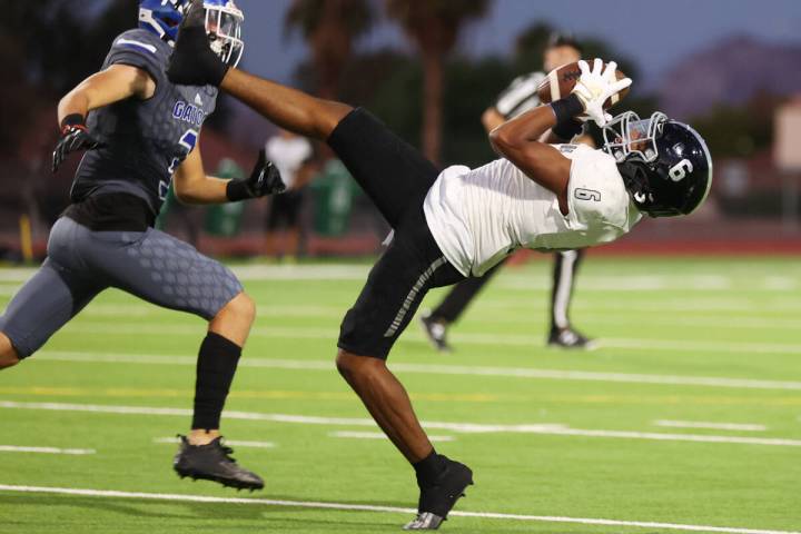 Desert Pines' Massiah Mingo (6) makes a catch under pressure from Green Valley's Blayne Reiner ...