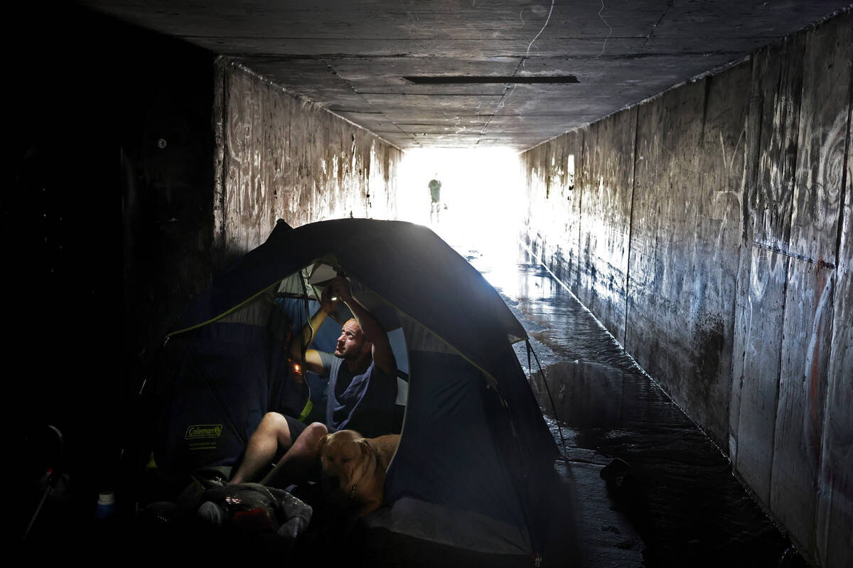 A.J., who declined to give his last name, adjusts a light in the flood control tunnel where he ...