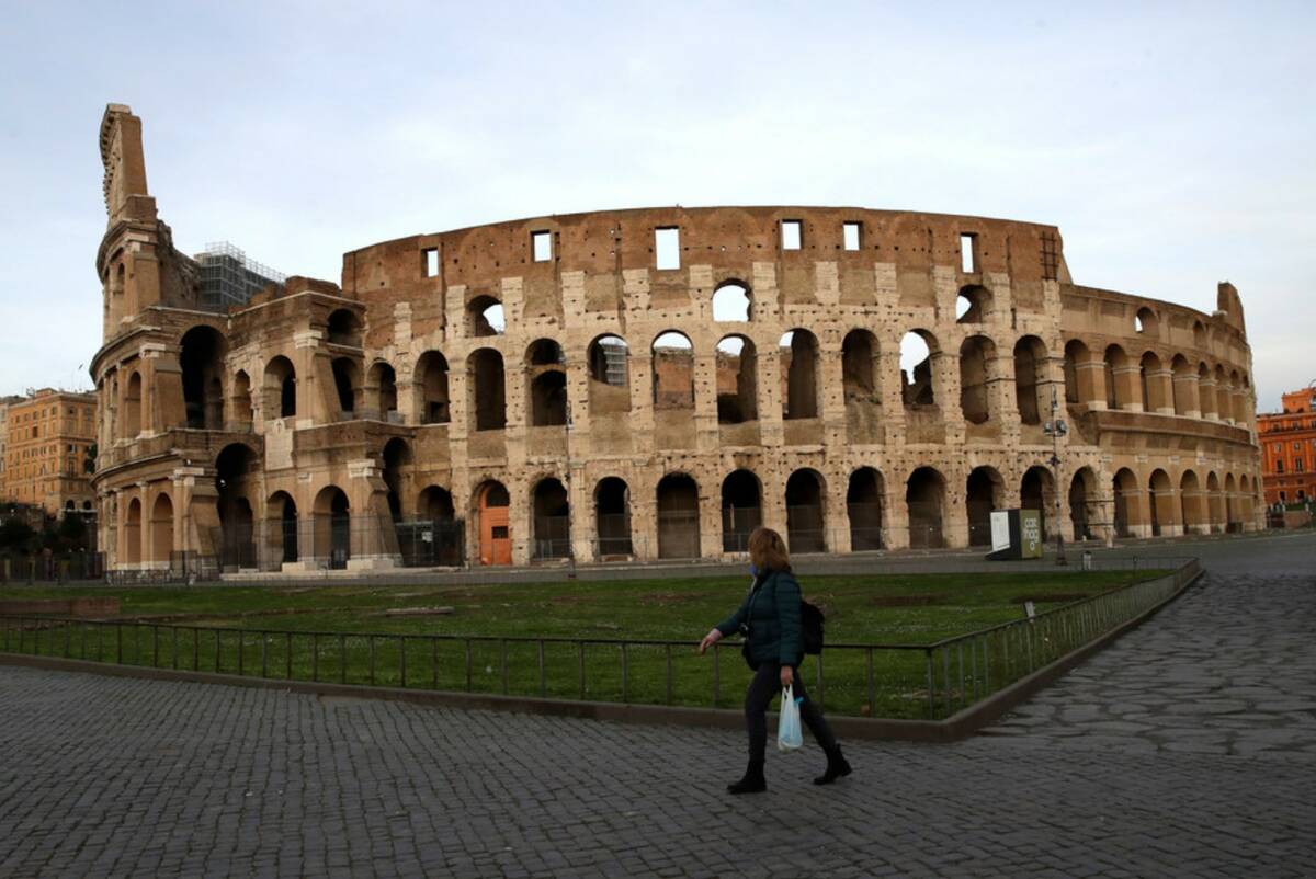 A woman walks in front of Rome's ancient Colosseum in March, 2020. (AP Photo/Alessandra Tarantino)