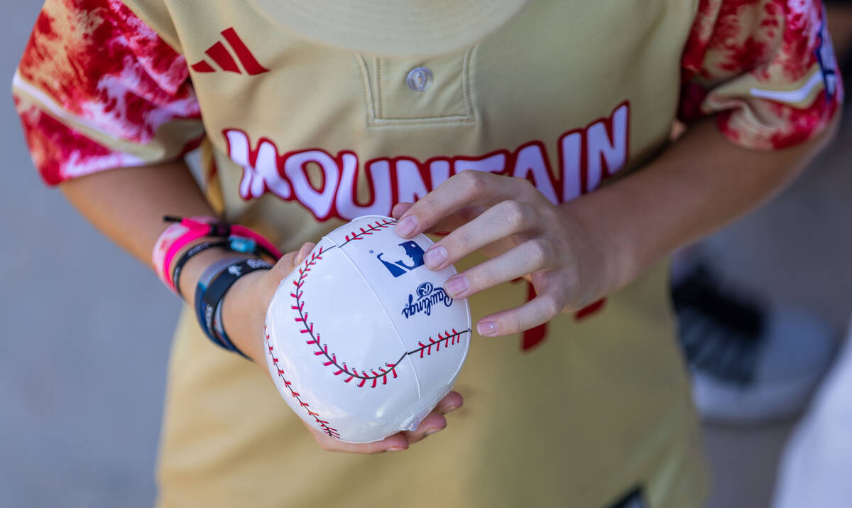 A Henderson Little League team player holds an inflatable baseball to throw to fans along their ...