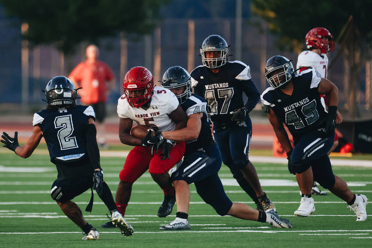 Arbor View running back Makhai Donaldson (5) holds onto the ball as Shadow Ridge defensive end ...