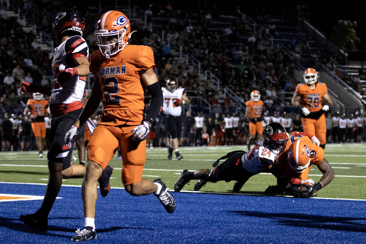 Bishop Gorman's Elija Lofton, right, dives into the end zone to score while tackled by Centenni ...