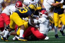 UNLV quarterback Doug Brumfield (2) is sacked by Michigan linebacker Michael Barrett (23), Maso ...