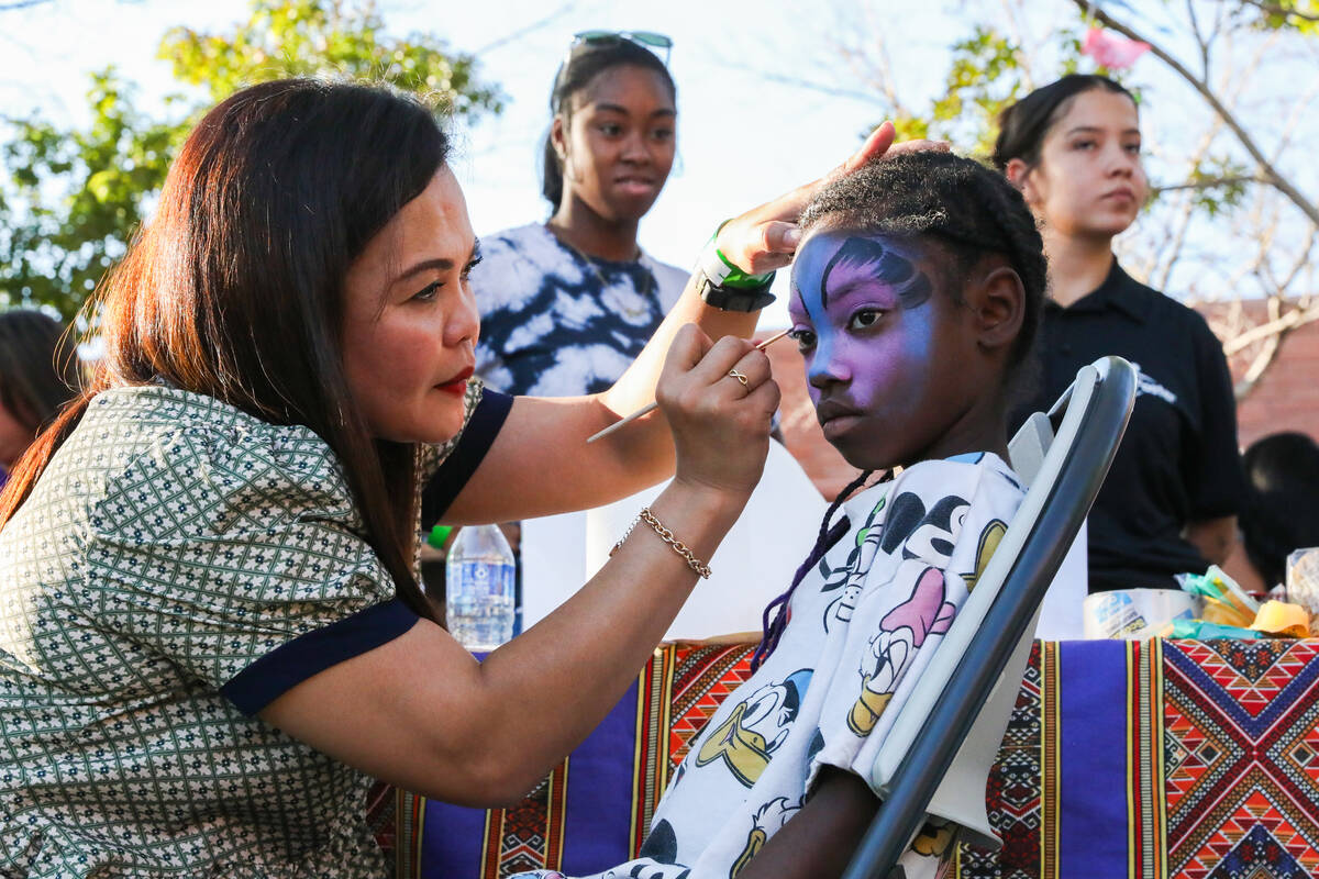 Herden Guevrra paints Jaeda Williams’ face at the Communities United, Raising The Stakes ...