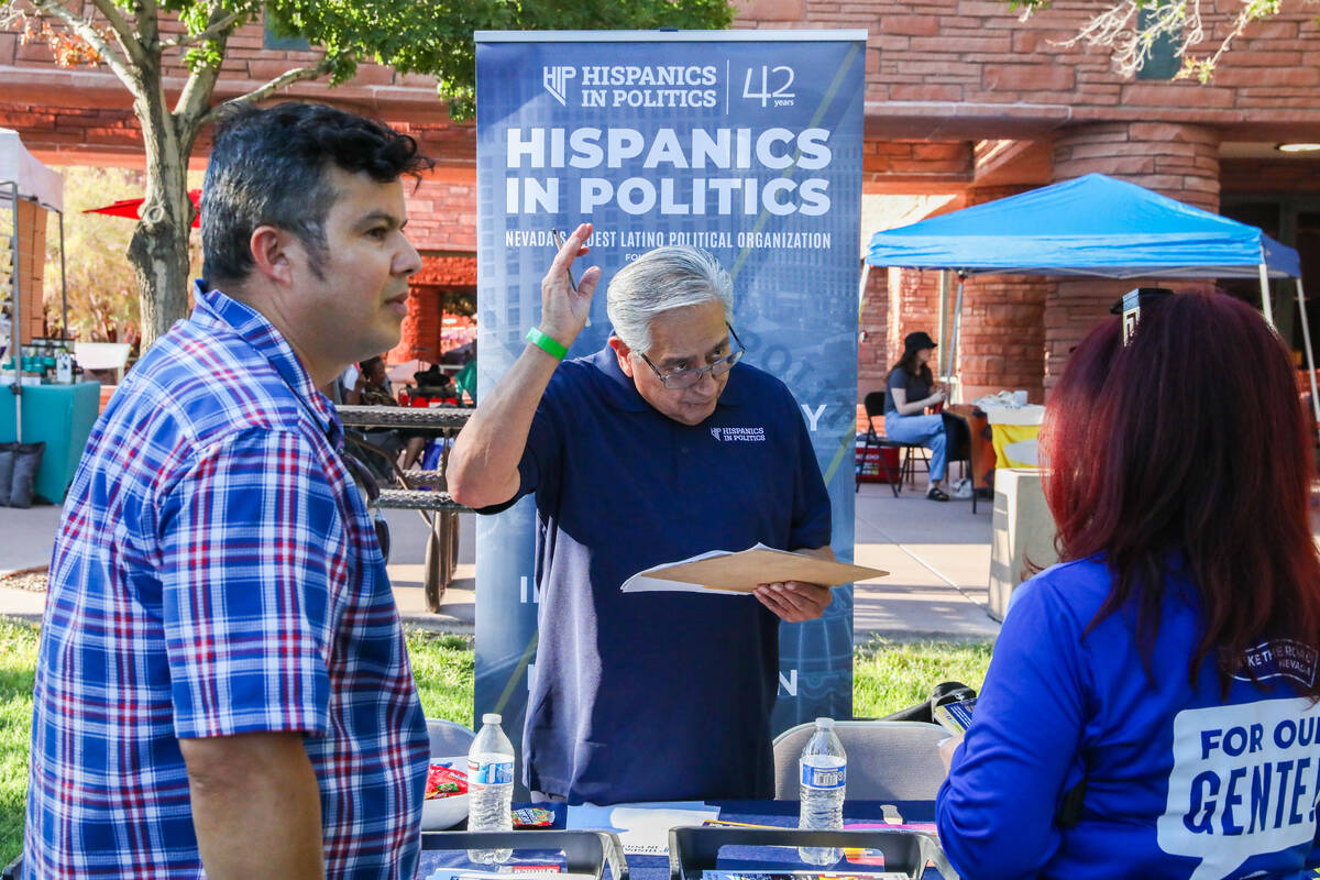Jacinto Alfaro, left, speaks with Fernando Romero at a booth for Hispanics in Politics at the C ...