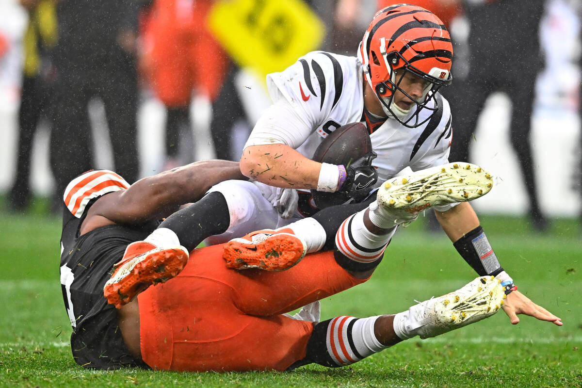 Cincinnati Bengals quarterback Joe Burrow (9) is sacked by Cleveland Browns defensive end Myles ...