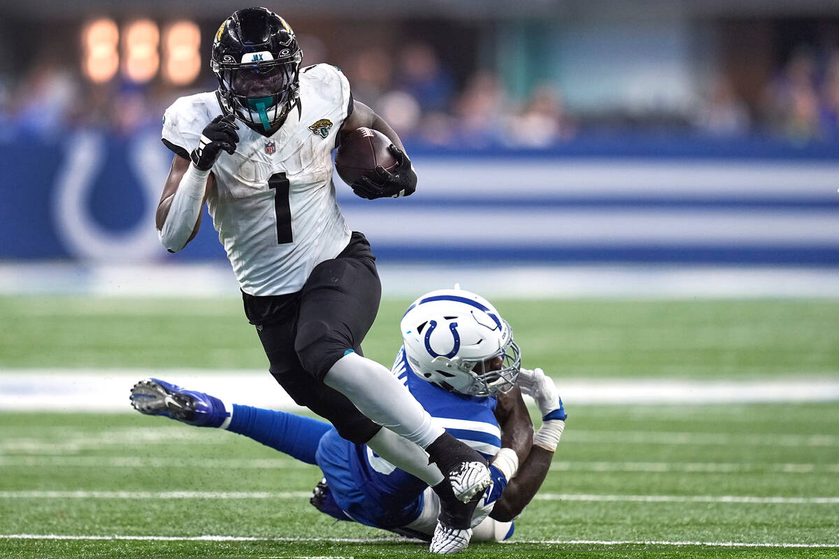 Jacksonville Jaguars running back Travis Etienne Jr. (1) slips past Indianapolis Colts lineback ...