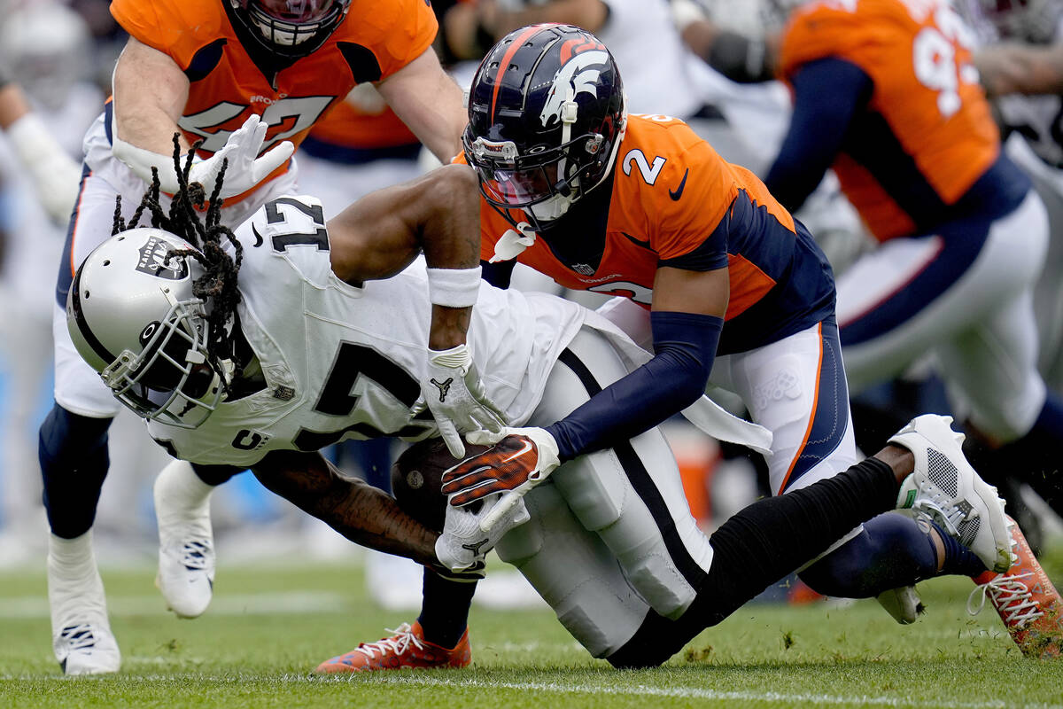 Las Vegas Raiders wide receiver Davante Adams (17) is hit by Denver Broncos cornerback Pat Surt ...