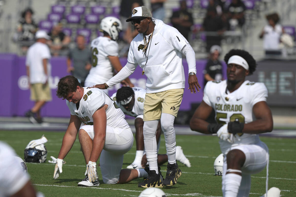 Colorado head coach Deion Sanders walks the field with his players warming up before an NCAA co ...