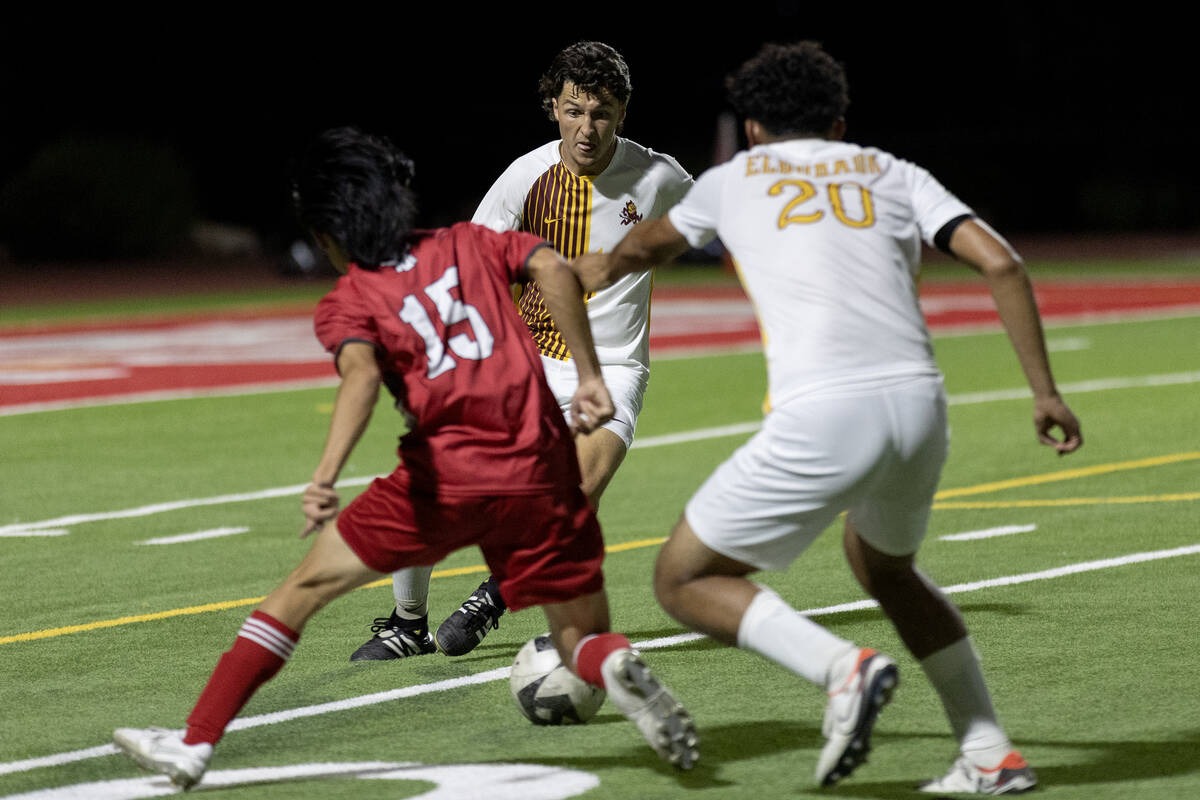 Eldorado’s Luke Ostler, center, receives a pass from teammate Jesse Garcia (20) while Ar ...