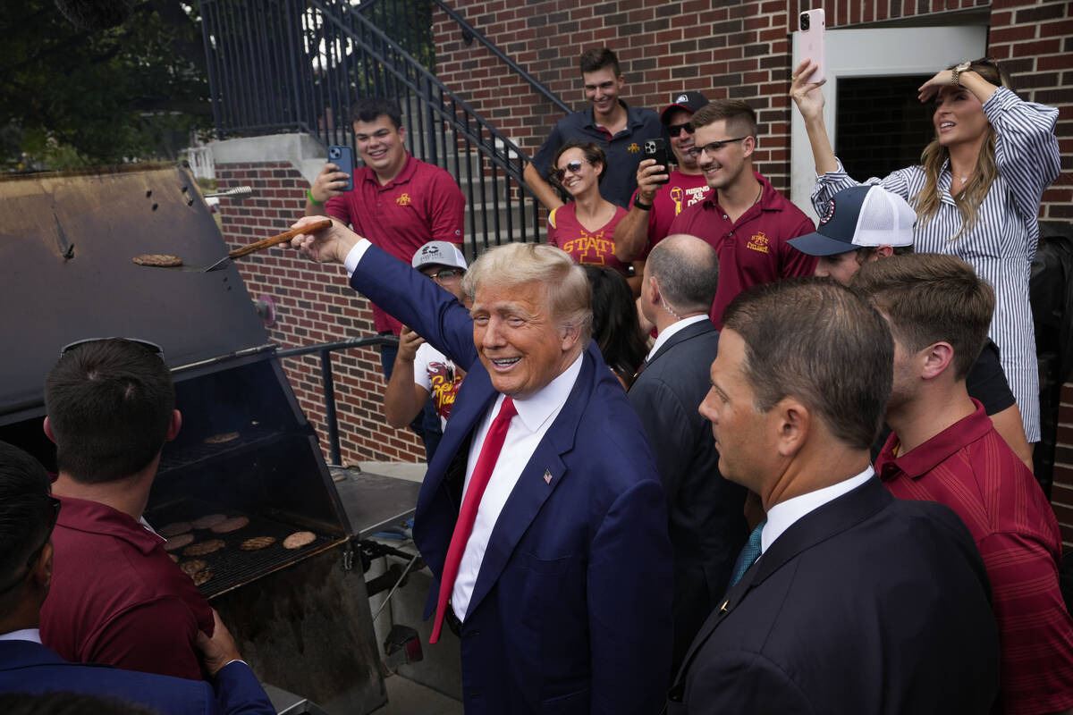 Former President Donald Trump holds a spatula with a hamburger on it as he works the grill duri ...