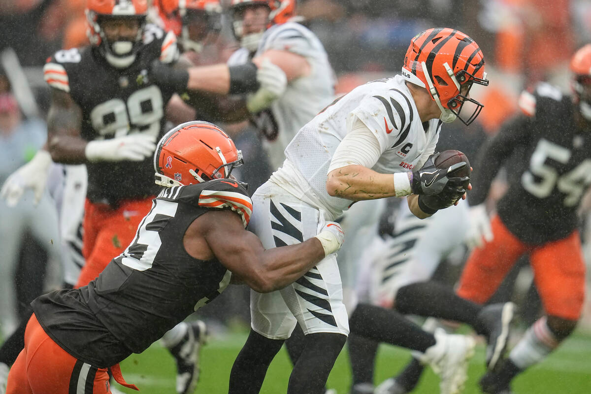 Cincinnati Bengals quarterback Joe Burrow (9) is pressured by and sacked by Cleveland Browns de ...