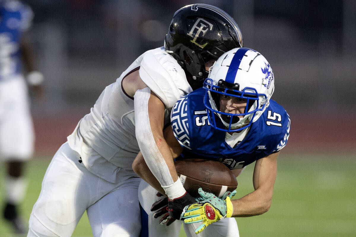 Faith Lutheran fast safety Gavin Day (12) tackles Basic wide receiver Anthony Dorlon (15) out o ...