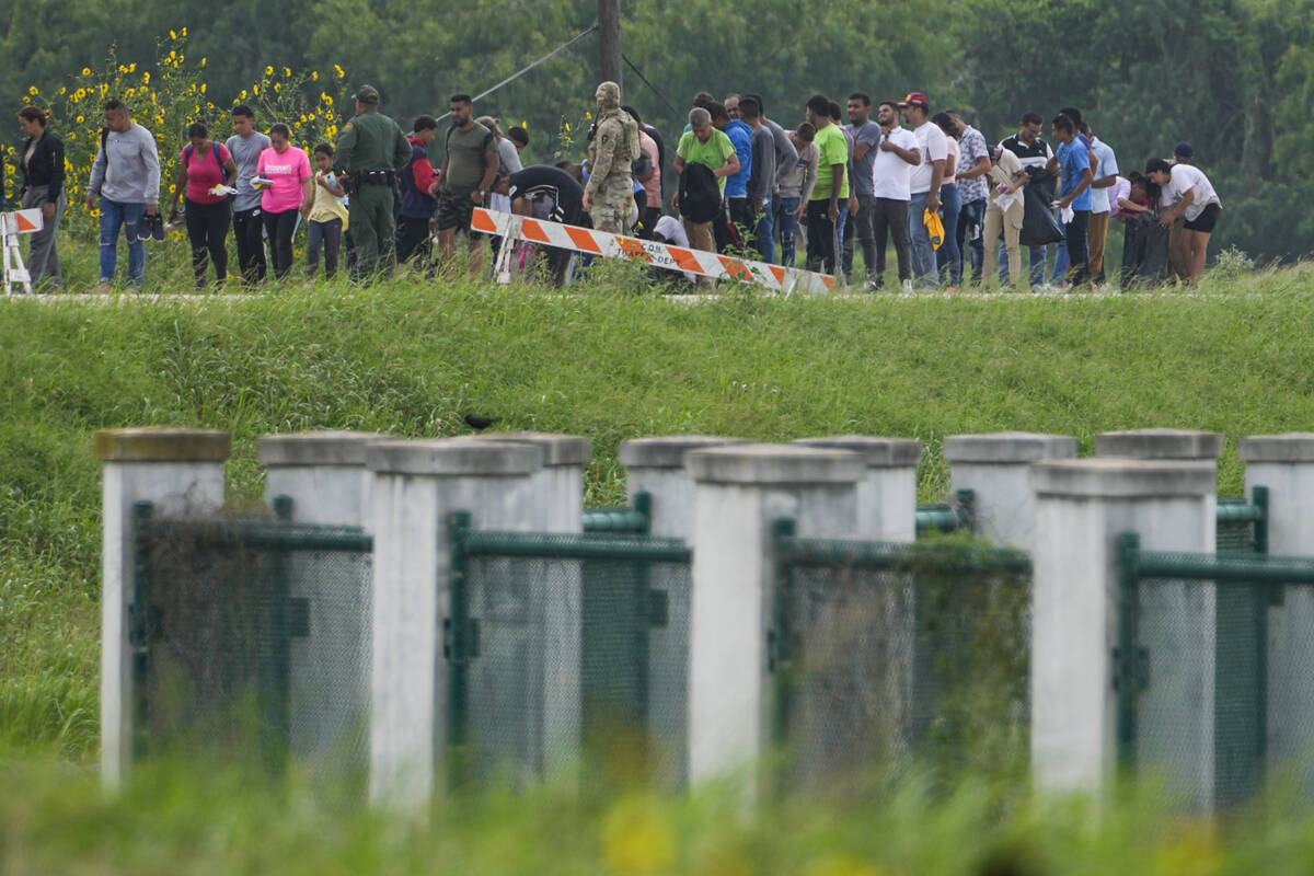 FILE - Migrants talk to officials along a road near the Rio Grande after crossing the Texas-Mex ...