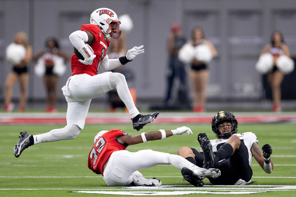 UNLV defensive back Jerrae Williams (1) leaps over defensive back Ricky Johnson (32) and Vande ...