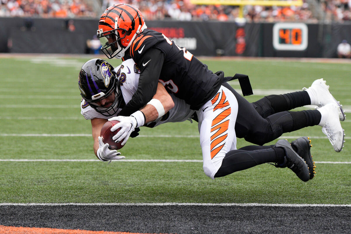 Baltimore Ravens tight end Mark Andrews scores as Cincinnati Bengals safety Dax Hill, top, defe ...