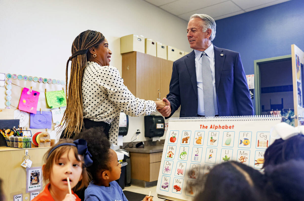 Gov. Joe Lombardo, right, shakes hands with teacher Jaquila Lewis, left, during a pre-K lesson ...