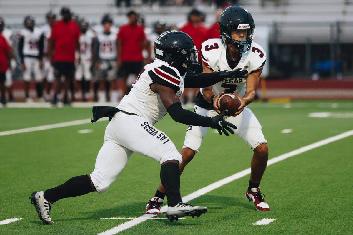 Las Vegas quarterback Tanner Vibabul (3) hands the ball off to running back Torrell Harley (7) ...