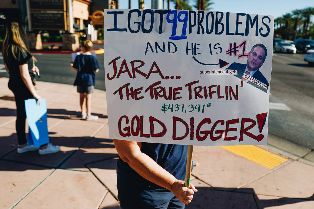 A protester, who did not want their face to be shown, holds up a sign directed at Dr. Jesus Sar ...